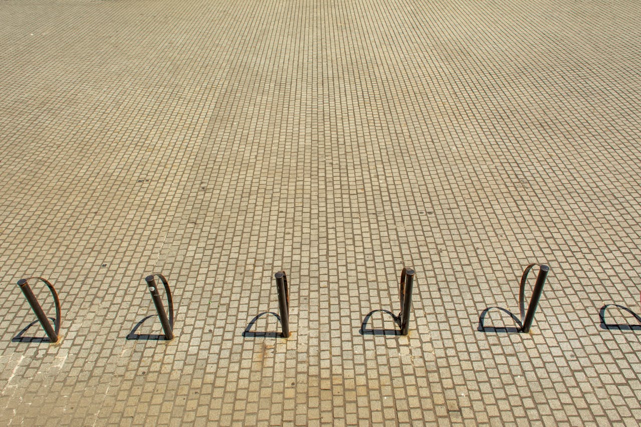 An empty cycle stand on a paved stone surface during daytime.